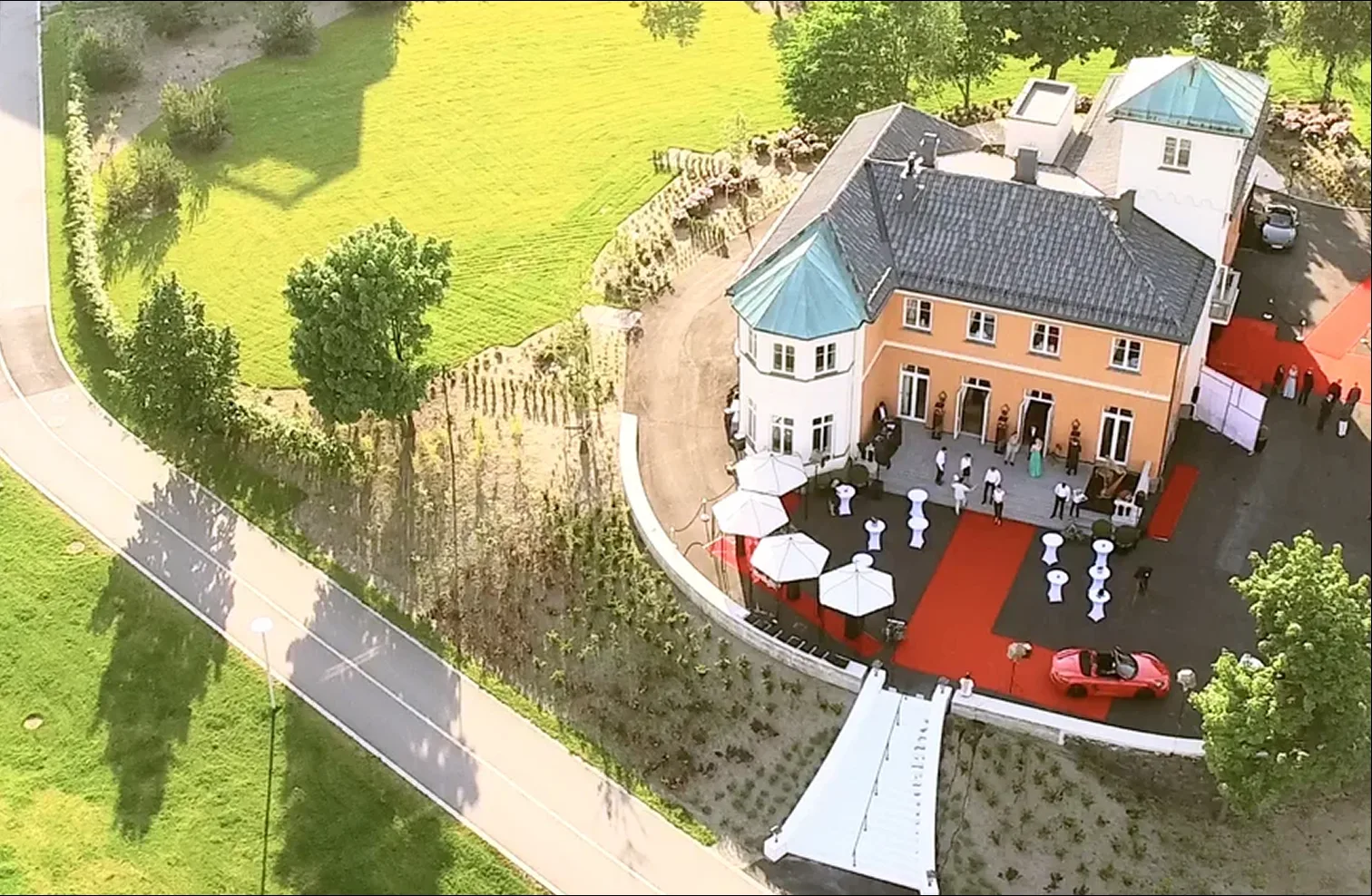 Bryllupsselskap med rød løper og parasoller foran Chitra House sett ovenfra